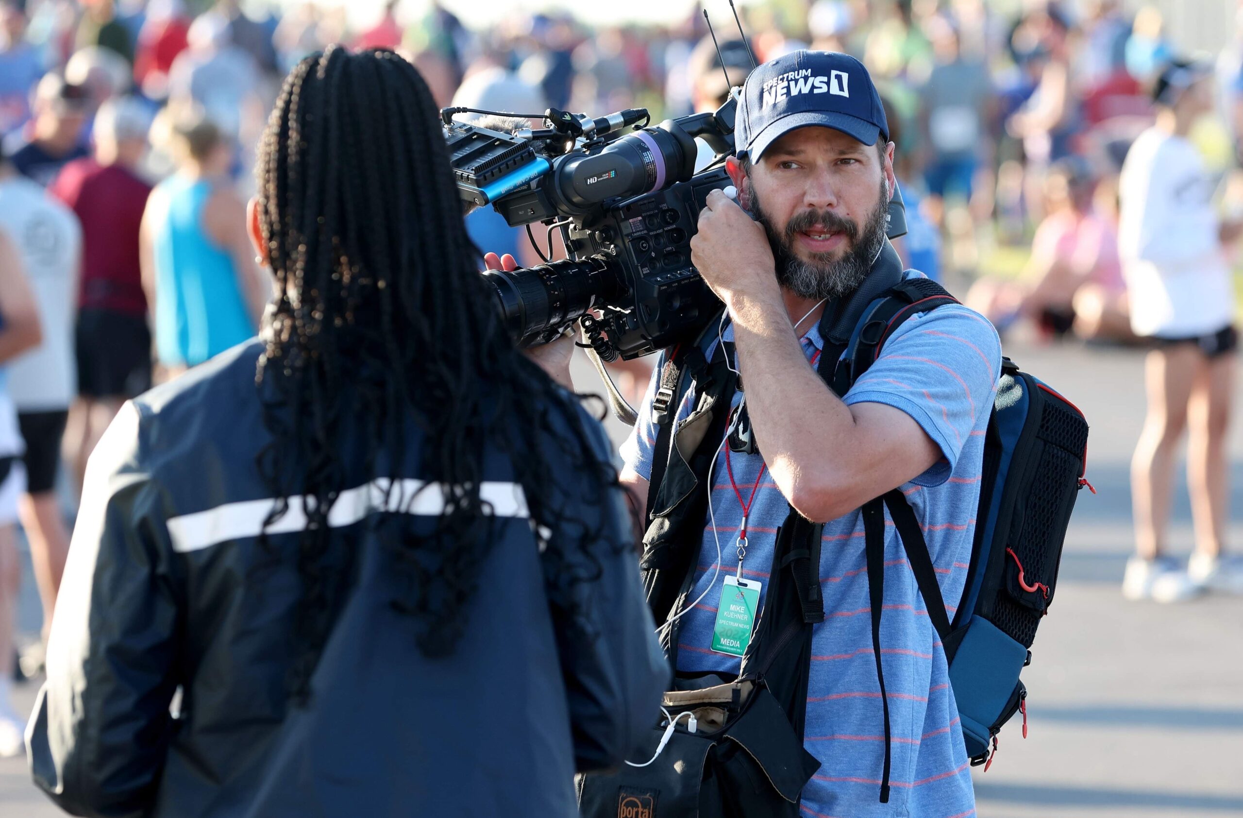 News photojournalist Mike Kuehner in the field with camera on his shoulder.